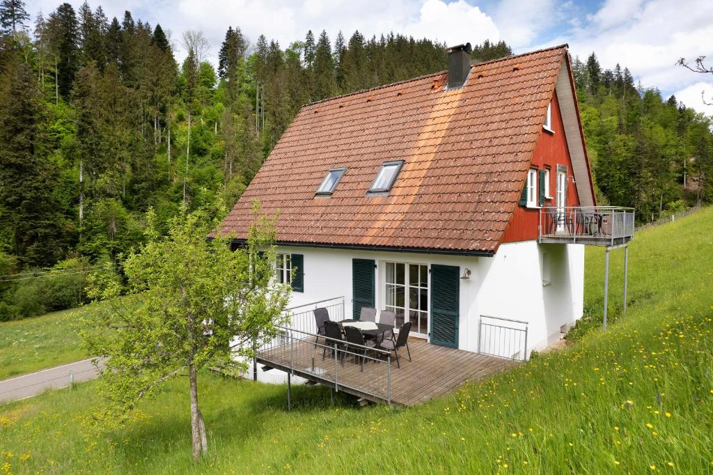 a small white house with a deck on a hill at Haus 1 Hanselishof - 2 Wohnungen in Schenkenzell