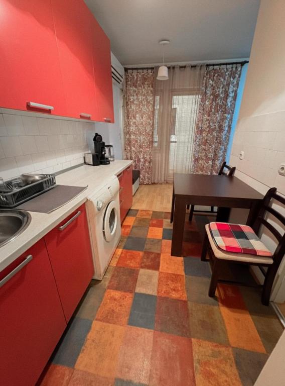 une cuisine avec des placards rouges et une table avec une salle à manger dans l'établissement Stan na dan Bačka Topola, à Bačka Topola