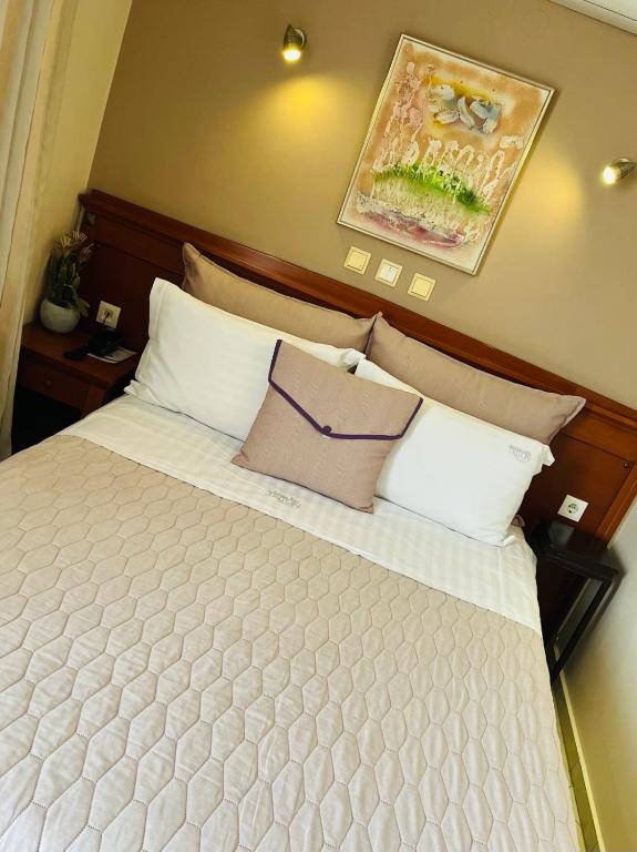 a bed with white pillows and a picture on the wall at Triton Hotel Piraeus in Piraeus