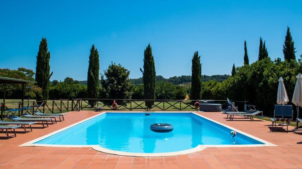 a large swimming pool with chairs and a wheel in the middle at Appartamento Mulino in Laterina