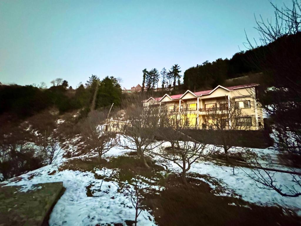 una casa en una colina con nieve en el suelo en Apple Tree Villa By Exotic Stays, en Shimla