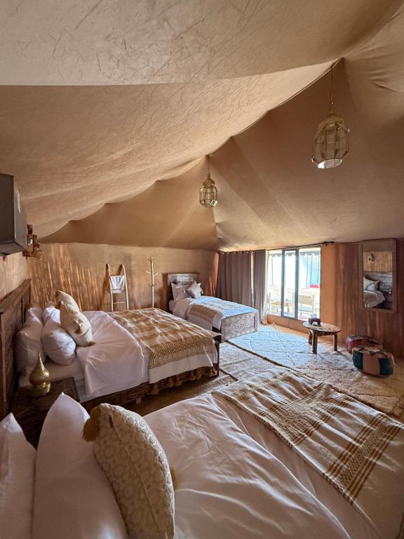 a large bedroom with two beds and a large window at Desert luxury tents in Merzouga