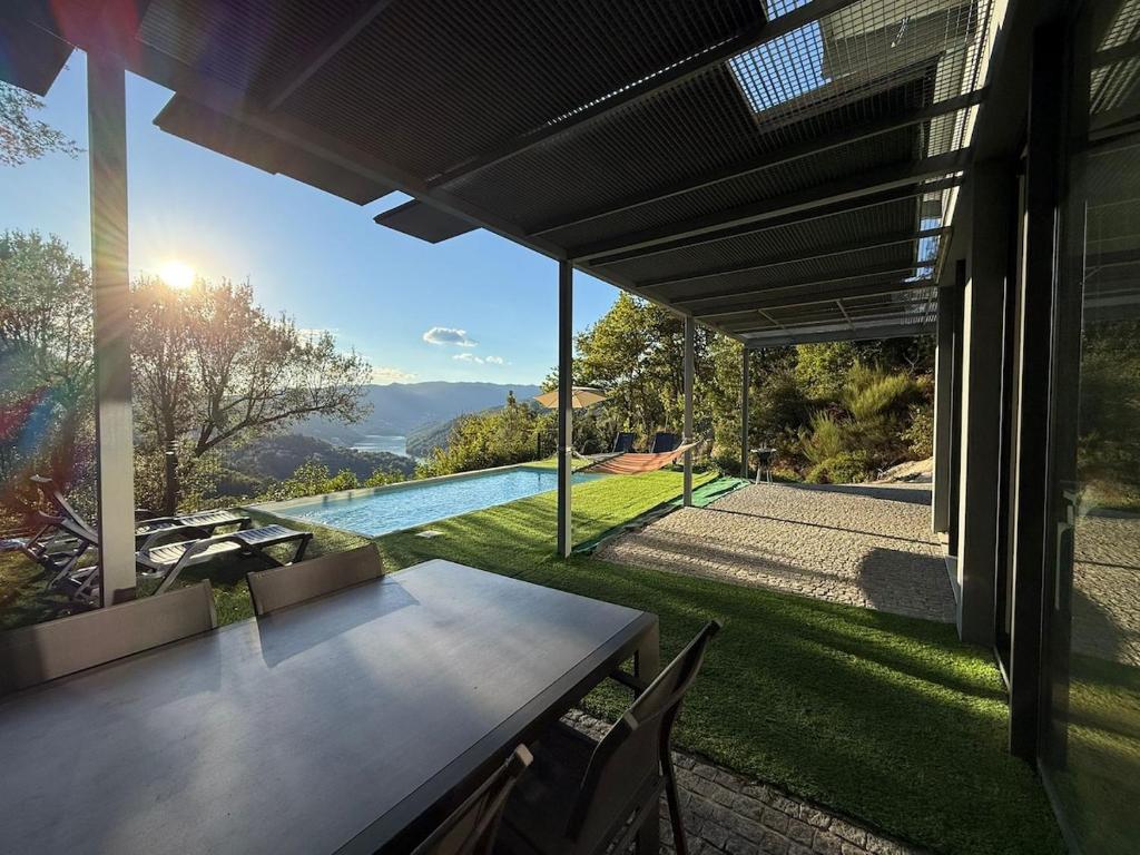 a patio with a table and chairs and a pool at Villa Teixugueiras 2 - Gerês in Vieira do Minho