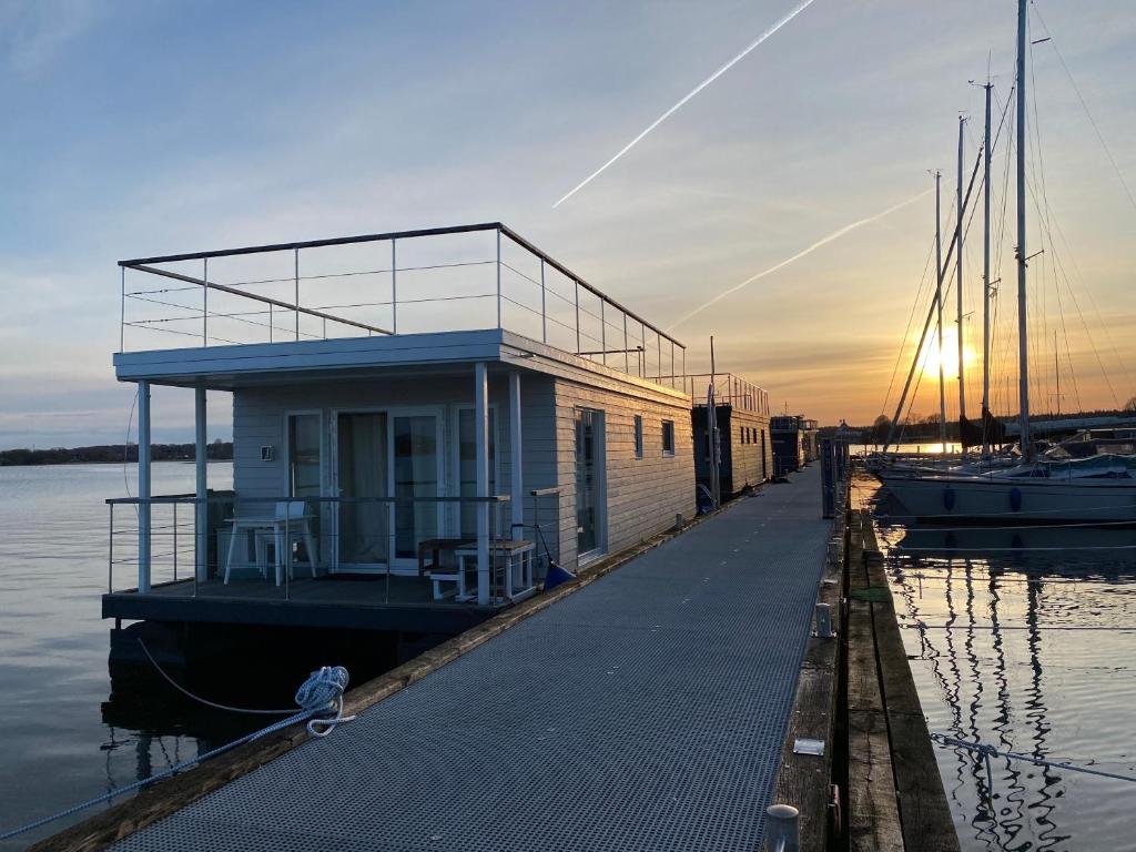 a building on a dock next to the water at Hausboot Koje Kaete mit großem Sonnendeck in Schleswig in Schleswig