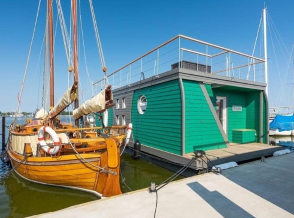 a boat is docked at a dock with a building at Hausboot Smaragd Heiligenhafen in Heiligenhafen