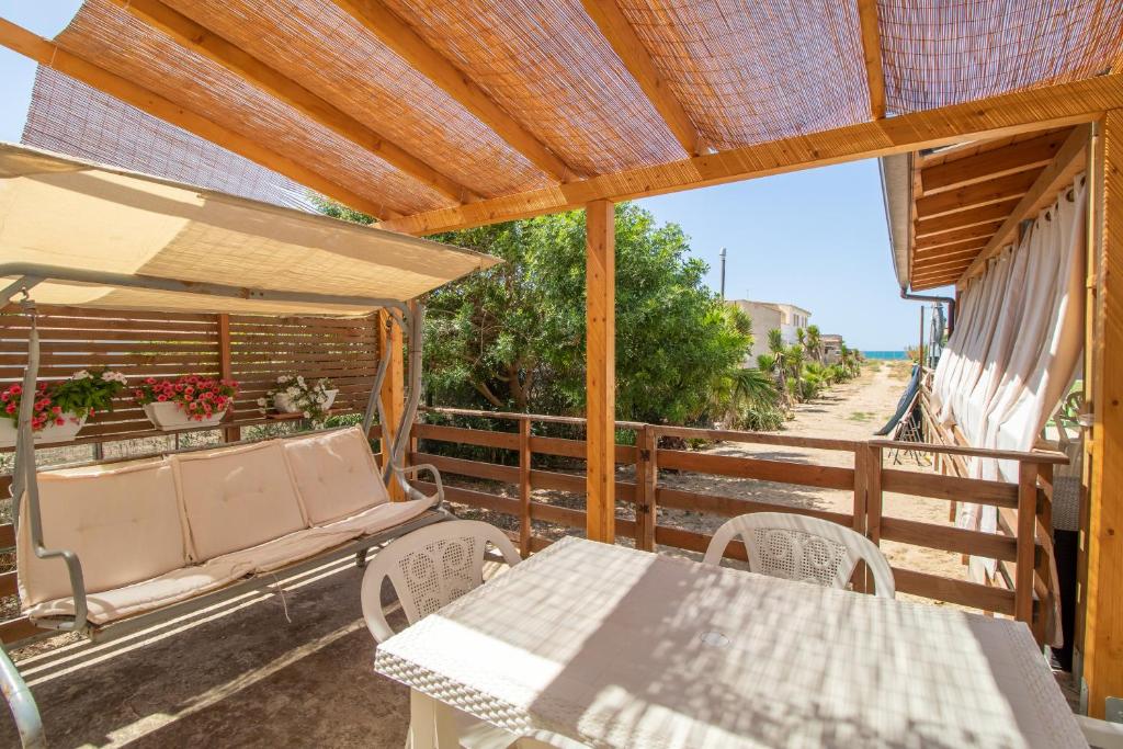 un patio con mesa, sillas y banco en Appartamento sul mare, en Case Cicirello