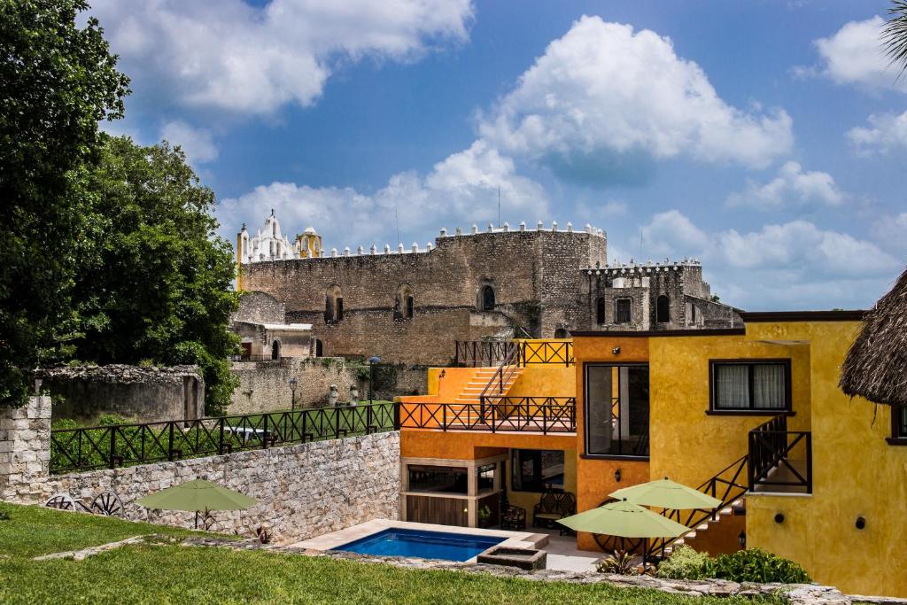 a building with a swimming pool in front of a castle at Hotel Rinconada del Convento in Izamal