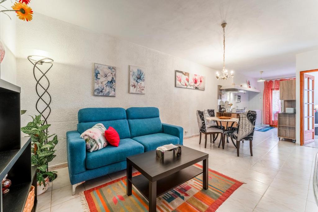 ein Wohnzimmer mit einem blauen Sofa und einem Tisch in der Unterkunft Le Taulignan in Vaison-la-Romaine