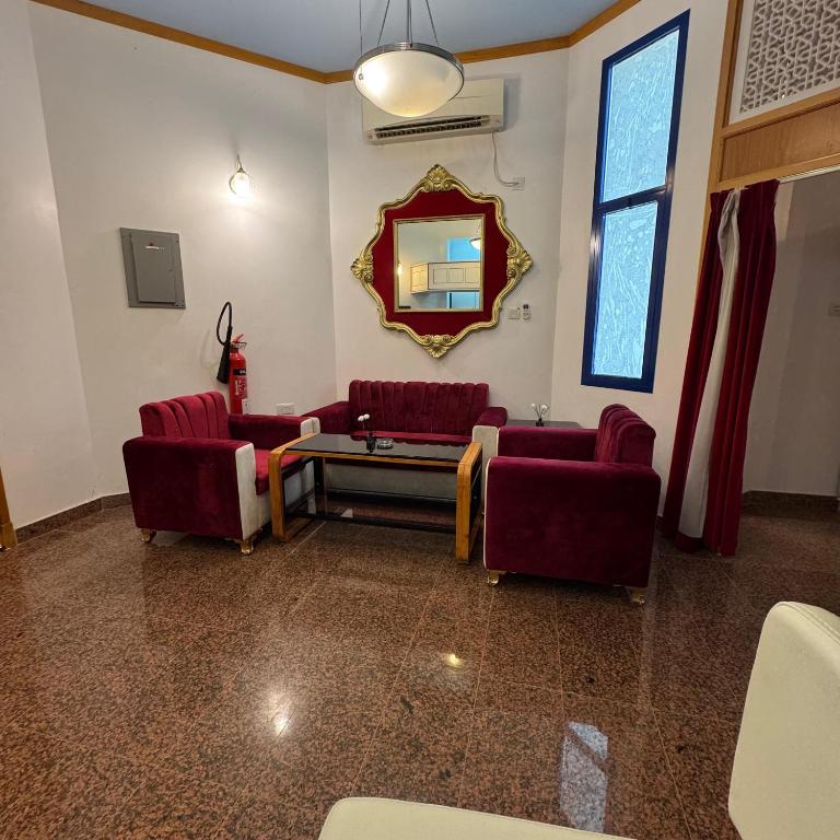 a waiting room with red chairs and a mirror at Qurum Heights Hotel in Muscat