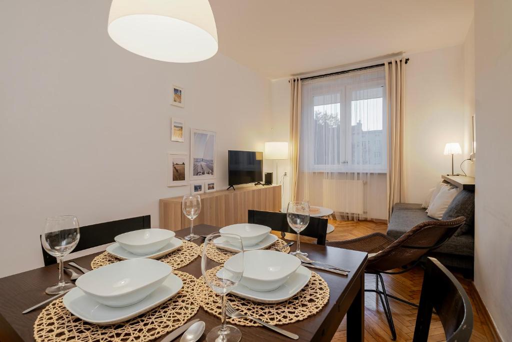Un comedor con una mesa con platos y copas de vino. en 5 Apart, en Gdynia