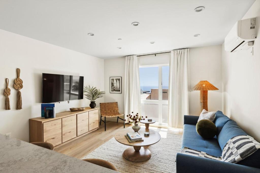 a living room with a blue couch and a tv at Tide House - Unit D - Modern Oceanview 1BD w Parking in El Segundo