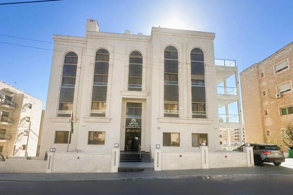 a large white building with a door in front at Masaken Hotel Apartment in Amman