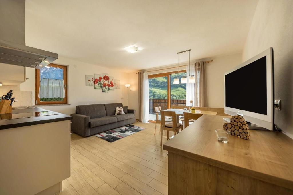 a kitchen and living room with a flat screen tv at Pfandlerhof Ferienwohnung Rot in San Martino