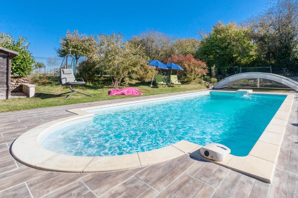 a swimming pool with blue water in a yard at Gîte Bricabroc 3 personnes in Noyant