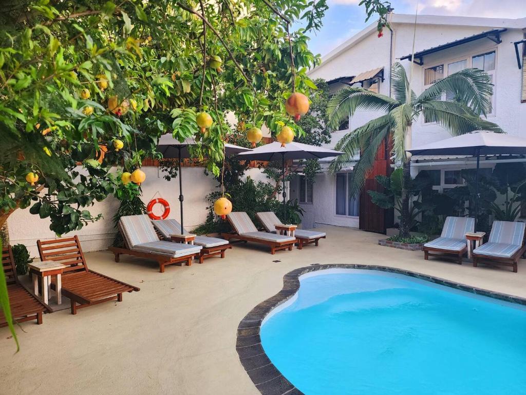 a swimming pool with lounge chairs and orange trees at Cozy 1-Bedroom Apt 3mins to Beach & Private Restaurant - TRR7 in Pointe aux Canonniers