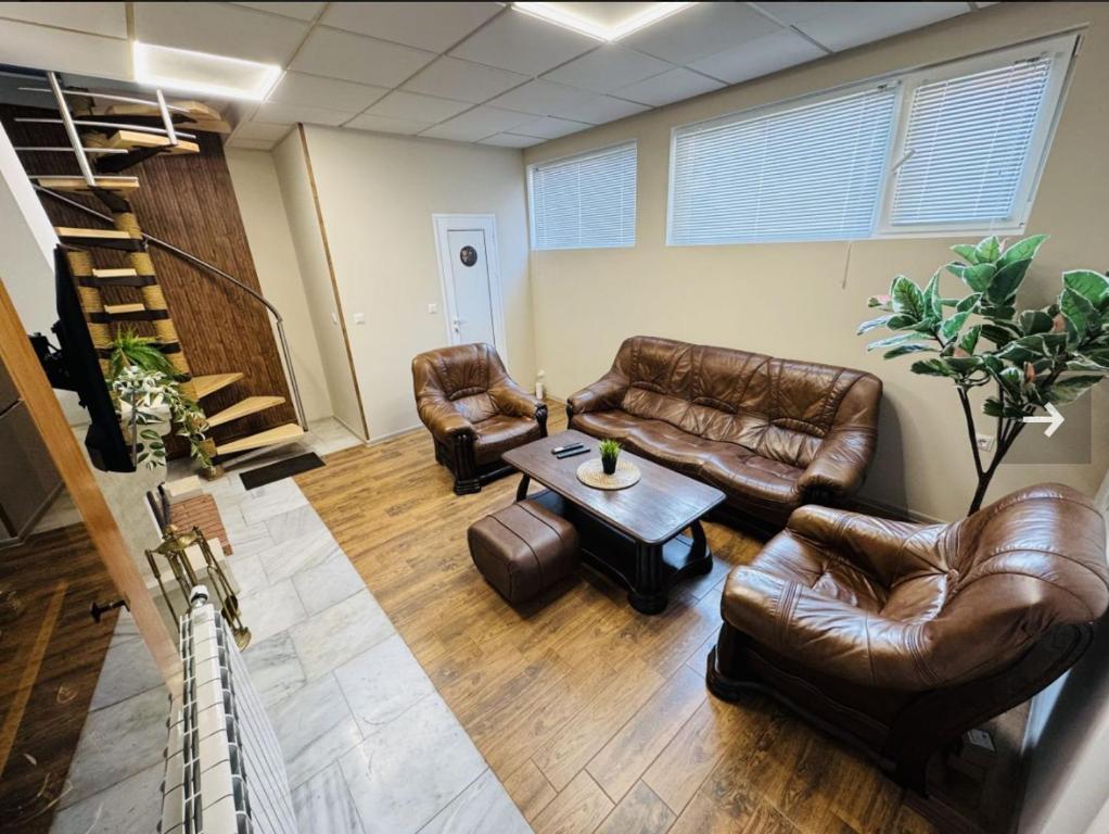 Una sala de estar con sofás de cuero y una mesa. en Guest house LORA, en Gabrovo