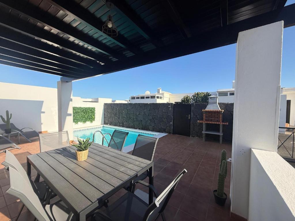 Un patio con mesa y sillas y una piscina. en Villa Vera, en Playa Blanca
