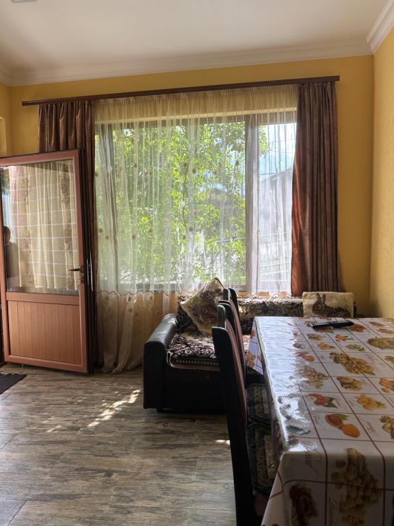 a room with a table and a couch and a window at Arpi GuestHouse Dilijan in Dilijan