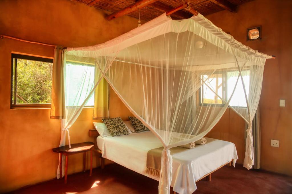 Tree House Cottage, Ocean View في بارايا دو توفو: غرفة نوم بسرير مع مظلة