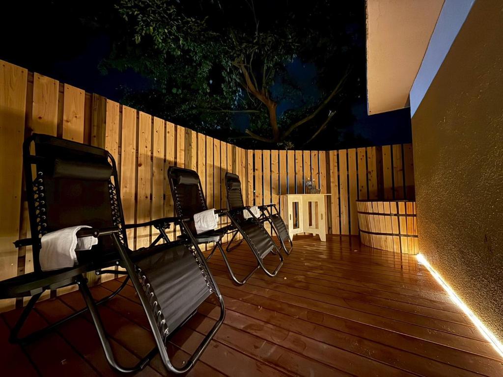 a row of chairs sitting on a wooden deck at 岳見の宿 天然温泉とプライベートサウナの一棟貸しヴィラ in Yufuin