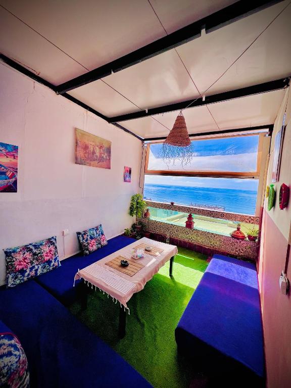 a living room with a table and a view of the ocean at TISLIT Surf Taghazout in Taghazout