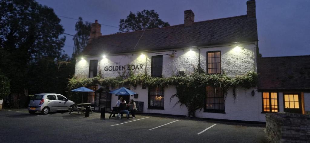 FreckenhamにあるThe Golden Boar Innの夜間外に座る人々のいる建物