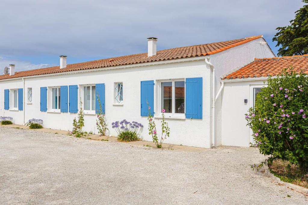 a white house with blue shutters and a driveway at Maison d'hôtes Le Grillon in La Brée-les-Bains