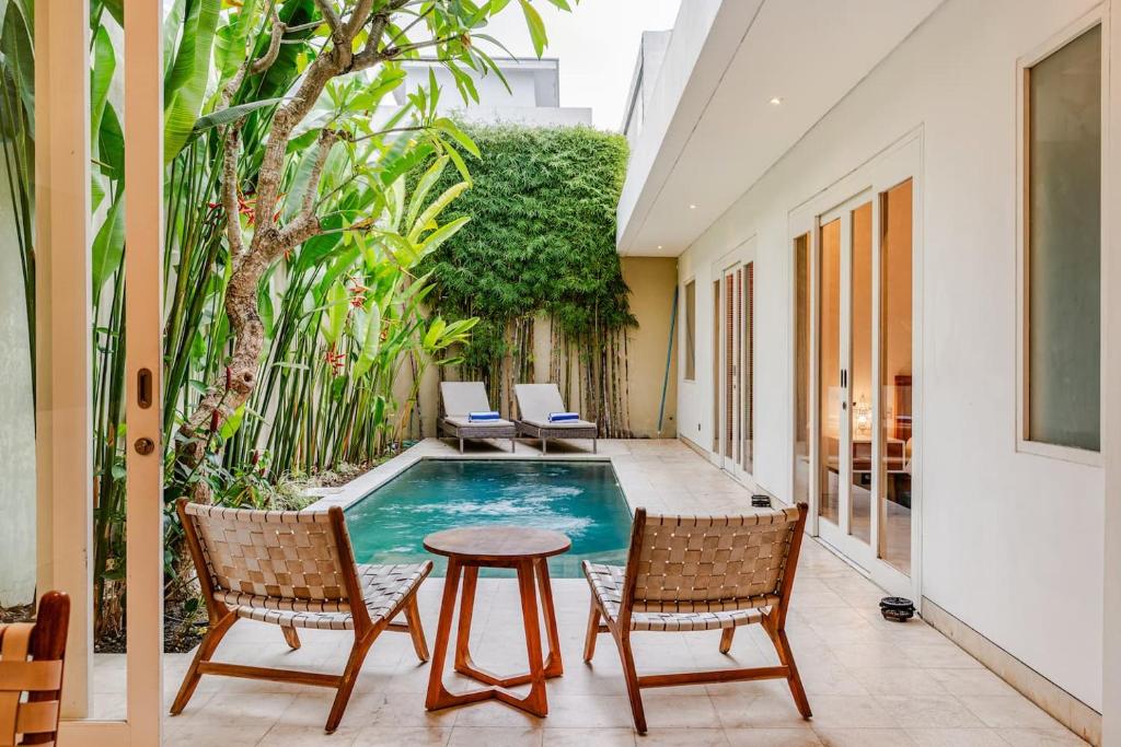une terrasse avec une piscine, 2 chaises et une table dans l'établissement Villa Vana, Sitara Villa Group, à Seminyak