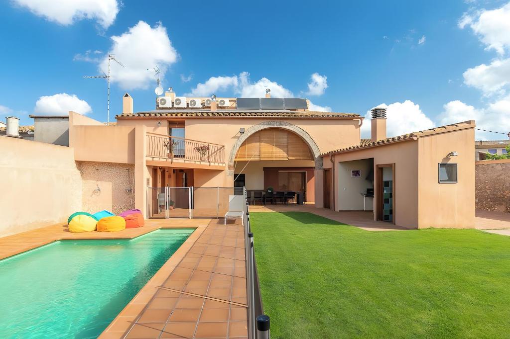 a house with a swimming pool and a yard at Can Centena in Vilamacolum