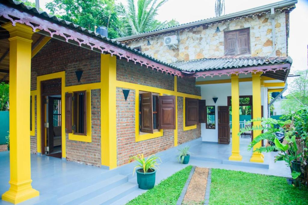 a brick house with yellow columns at ABS Villa Bentota in Bentota