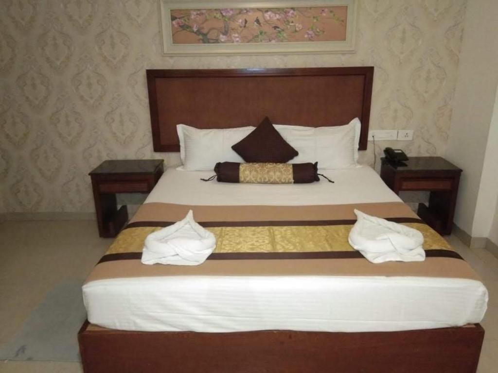 Un dormitorio con una cama grande con dos mesas. en Budget Hotel, en Khammam