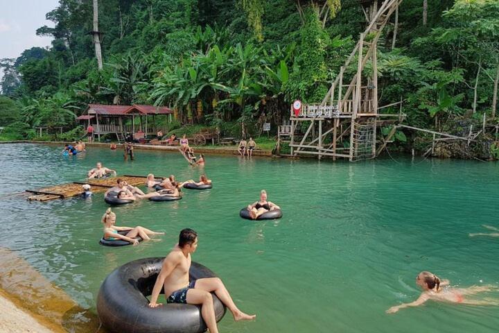 Eine Gruppe von Menschen befindet sich auf Schwimmreifen im Wasser. in der Unterkunft The Rock House Hostel in Vang Vieng