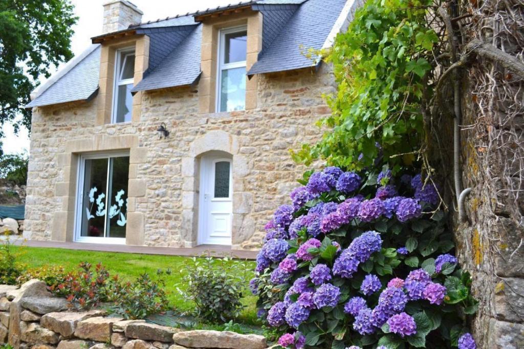 a stone house with purple flowers in front of it at A la Ferme du Cosquer in Baden