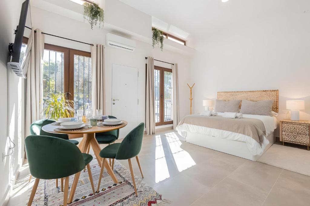 a white bedroom with a bed and a table and chairs at Oasis Del Candado in Málaga