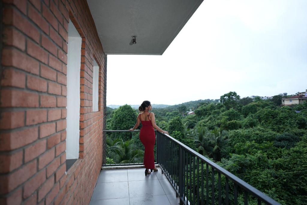 une femme en robe rouge debout sur un balcon dans l'établissement Hotel Casa De Patio, à Porvorim