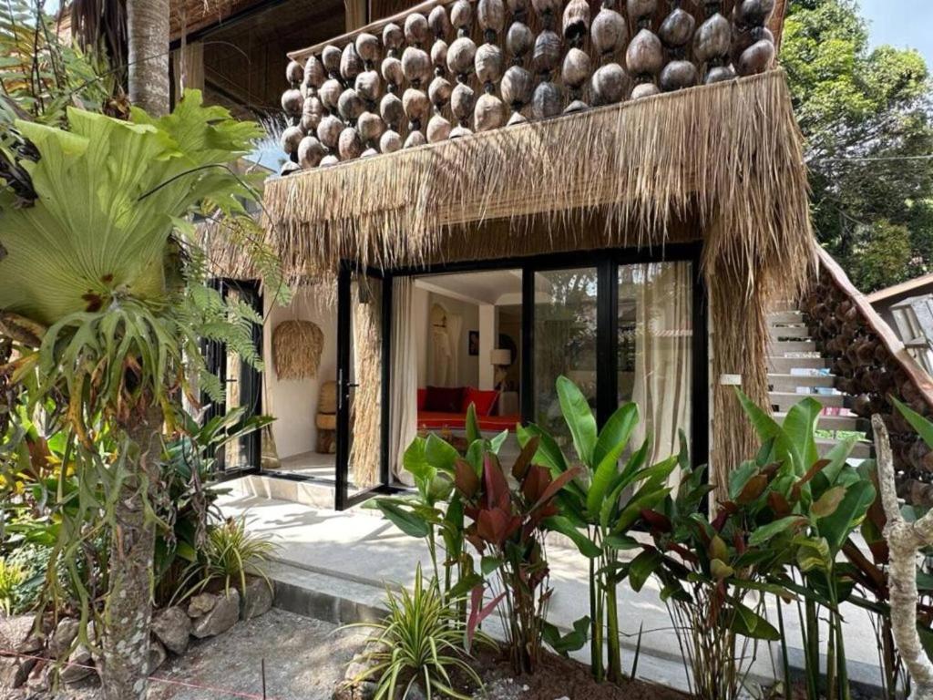 una casa con un tetto di paglia e alcune piante di Happy Coco Monkey - Cozy Studio by SP Villa a Ko Phangan
