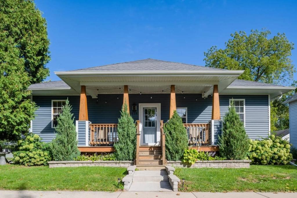 a blue house with a front porch and columns at Downtown 2BR Home - Lawrence University College Ave in Appleton