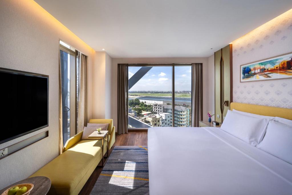 a hotel room with a large bed and a large window at Hyatt Place Dhaka Uttara in Dhaka
