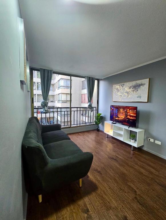 uma sala de estar com um sofá e uma TV de tela plana em Teatinos Departamentos STGO em Santiago