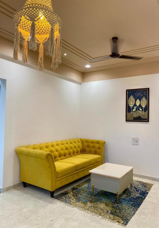 a yellow couch in a room with a table at Go-kul Homestay in Kolhapur