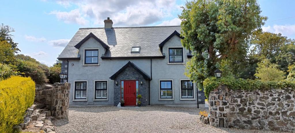 a house with a red door and a stone wall at Gateside Lodge in Portrush
