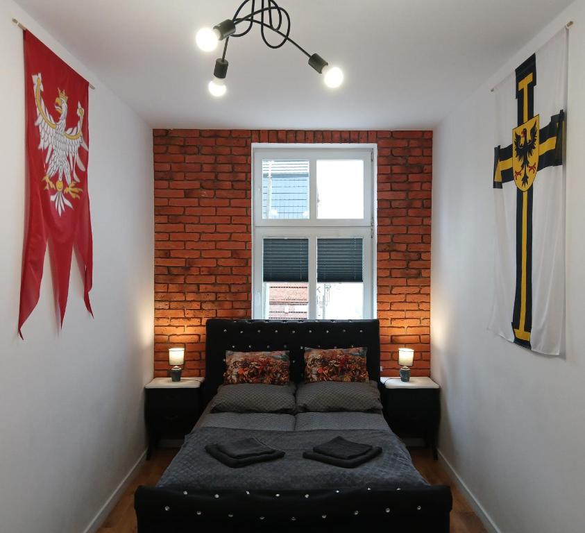 une chambre avec un lit et un mur de briques dans l'établissement Apartamenty Zakonne "Apartament Wielkiego Mistrza", à Malbork