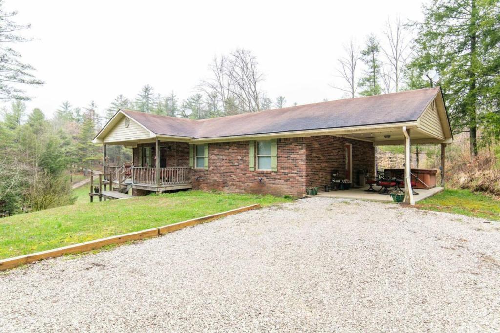 ein Backsteinhaus mit Veranda und Auffahrt in der Unterkunft Hot Tub & WiFi -Carrie's Cottage - Red River Gorge in Pine Ridge