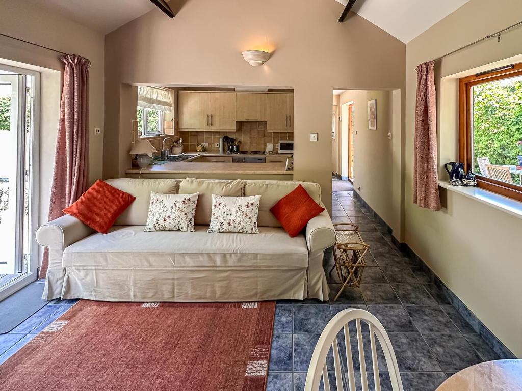 un salon avec un canapé et une cuisine dans l'établissement Blossom's Cottage, à Albourne