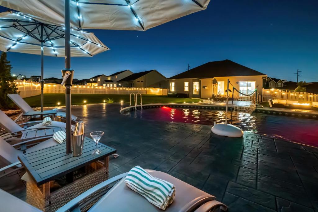 a pool with a table and chairs and an umbrella at Spacious Country Farmhouse Retreat, Sleeps 16, Pool, Movie Room in Papillion