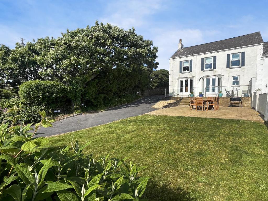 a white house with a table and chairs in the yard at Upper White Gates in Little Haven