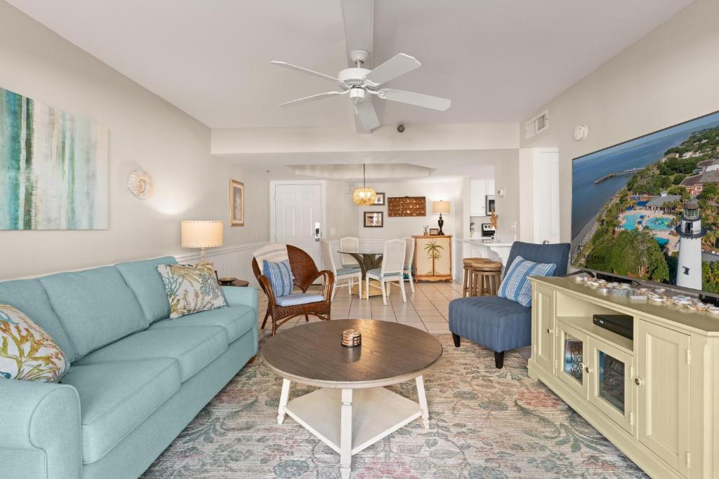 a living room with a blue couch and a table at Beach Club, Unit 134 in East End