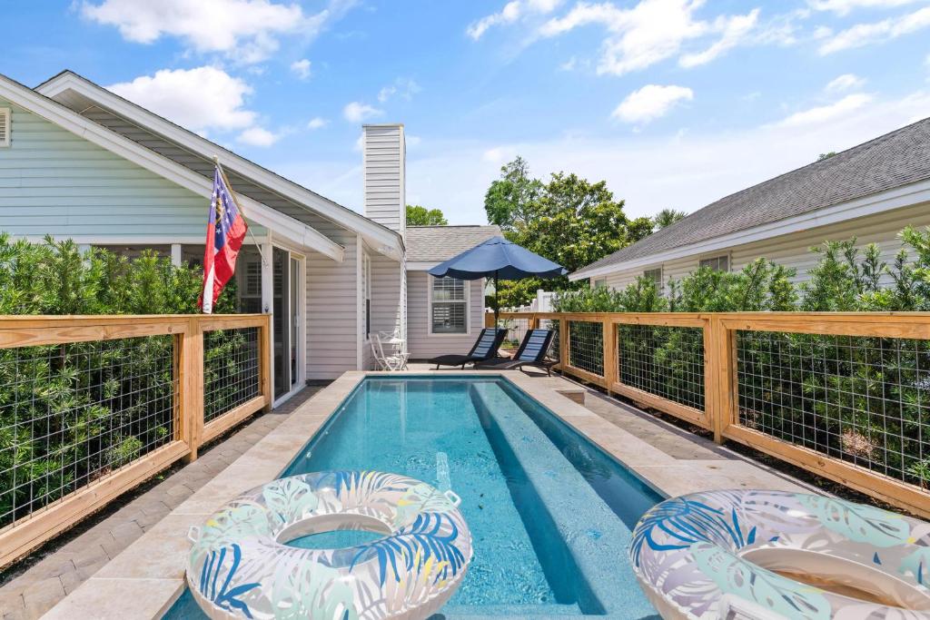 a swimming pool with two chairs and an umbrella at Point Five - 1133 Mallery St in Saint Simons Island