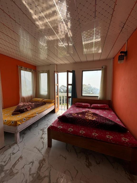 Duas camas num quarto com paredes e janelas cor-de-laranja em Sathwik Homestay em Takdāh