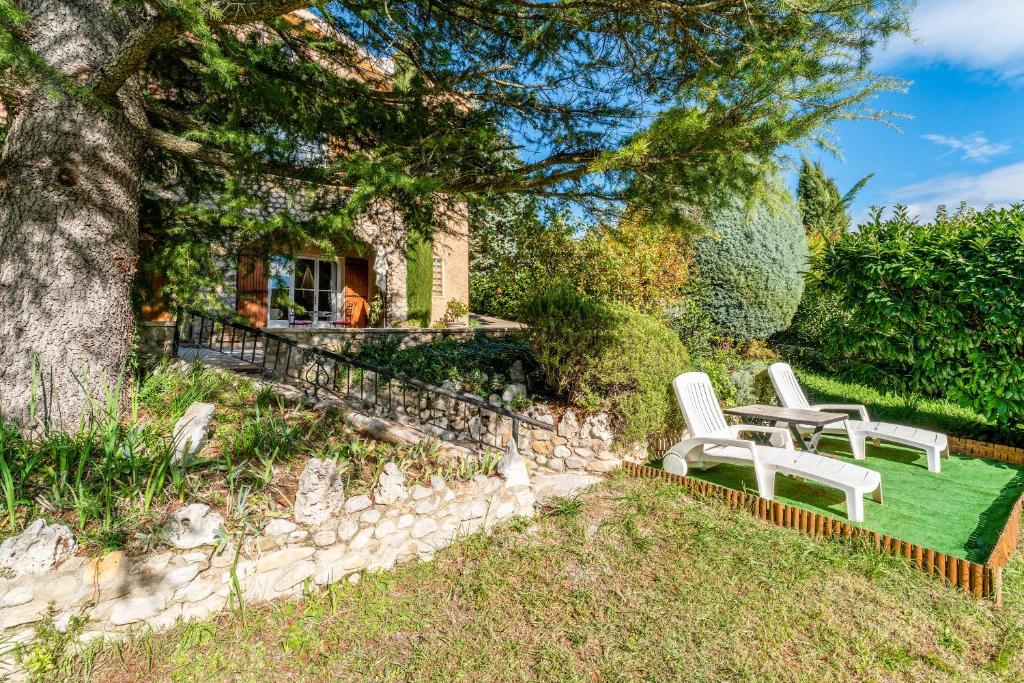 einen Garten mit zwei weißen Stühlen und einem Baum in der Unterkunft Gîte Le Séguret in Entrechaux
